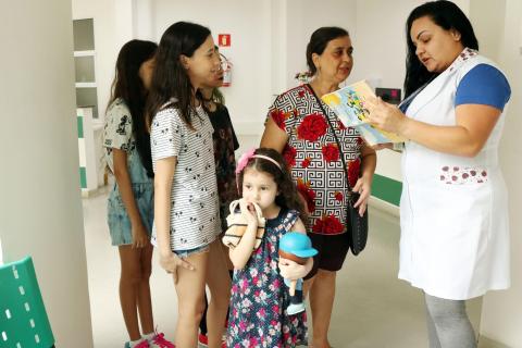 fila de meninas se forma enquanto técnica confere caderneta #pracegover