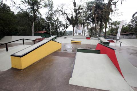 Pista de skate vazia, com conjunto de cinco rampas e pipnturas em amarelo e vermelho