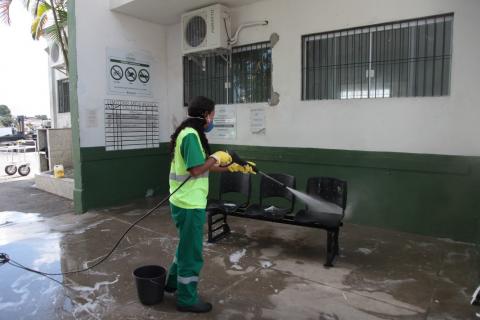 Mulher esguicha jato d'água em banco na entrada de cemitério. #Paratodosverem