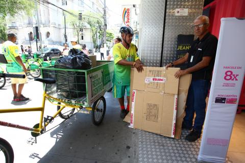 Homem está ao lado de bicicleta que recolhe material reciclável #pracegover 
