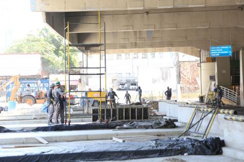 Trecho de baias com piso demolido. Homens estão próximos a andaime. #Paratodosverem
