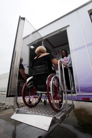 Mulher em cadeira de rodas é elevada em plataforma até a carreta #pracegover 