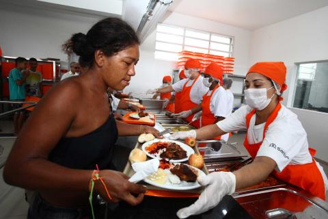 mulher pega bandeja com comida de funcionários #pracegover 