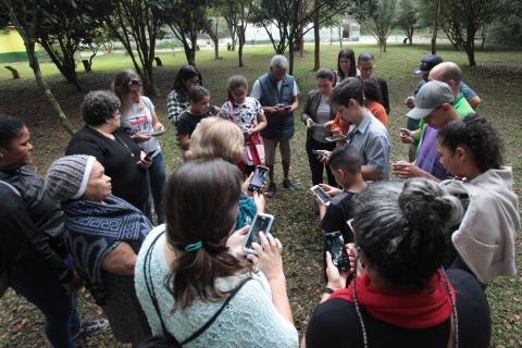 Alunos em círculo mexem em seus celulares #pracegover 