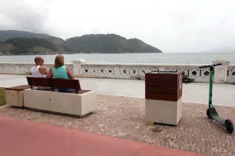 casal sentado em novo banco olhando o mar #pracegover 