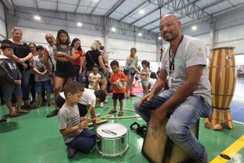 homem e crianças tocam instrumentos de percussão #pracegover 