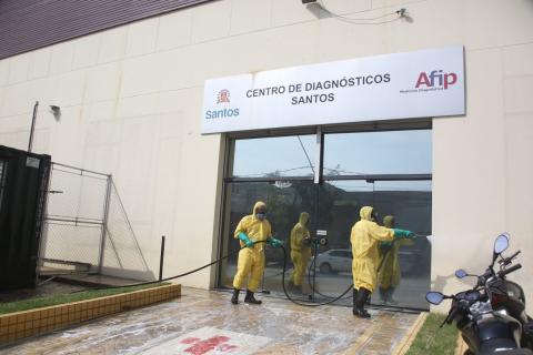 Fachada da Afip sendo higienizada por dois homens uniformizados. Eles usam esguichos de água. #Paratodosverem