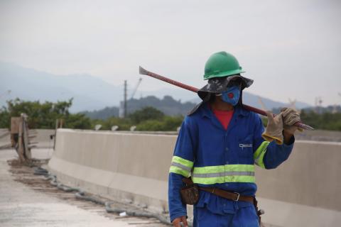 operário caminha sobre viaduto com ferramenta #paratodosverem 