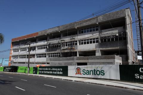 Fachada da escola com três andares e tapume na frente. #Pracegover