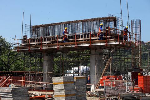 Um dos pilares com operários andando em cima #pracegover 