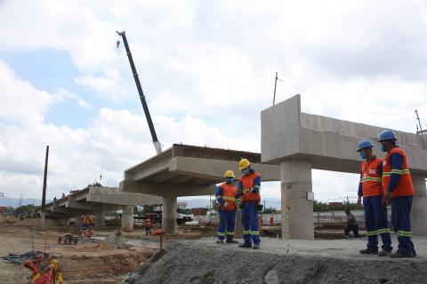 operários no canteiro ao lado de estrutura da ponte #paratodosverem 