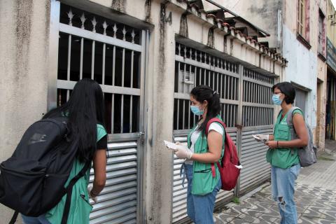 agentes na porta de casa com folhetos #paratodosverem 