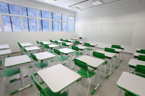 Uma das salas de aula, com mesas e cadeiras. #Pracegover