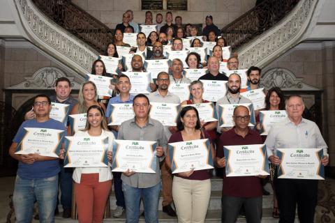 Todos os homenageados posam para foto na escadaria do hall de entrada da prefeitura. #Paratodosverem