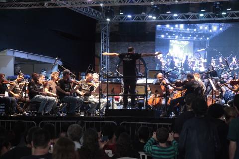 Orquestra Sinfônica de Santos está no palco. Maestro rege o grupo. #Pracegover