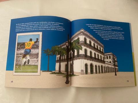 Página do livro aberta com foto de Pelé, de costas, e do Museu que leva o nome do Rei. #Paratodosverem