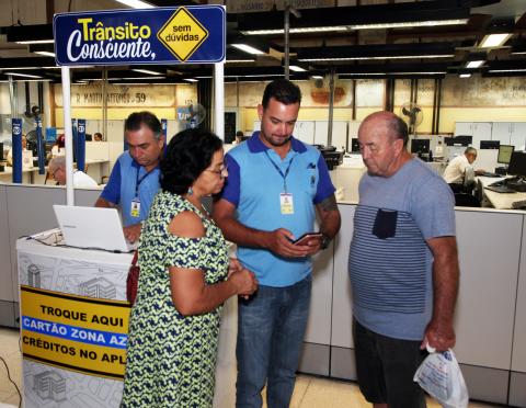 Pessoas observam agente orientando sobre a zona azul digital #pracegover 