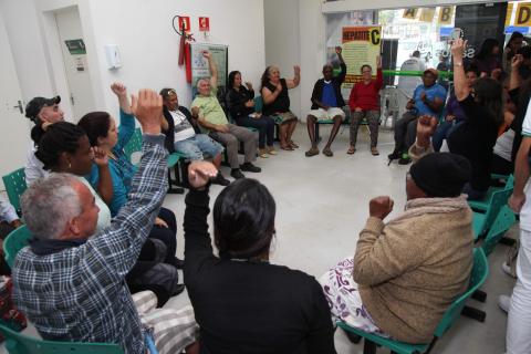 moradores levantam as mãos durante roda de conversa #pracegover