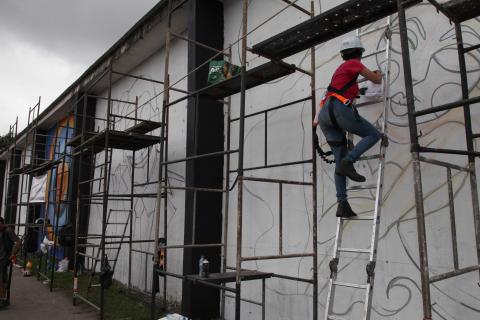 homem faz grafite no muro #pracegover 