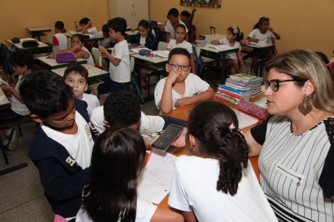 professora está com alunos na mesa #pracegover 