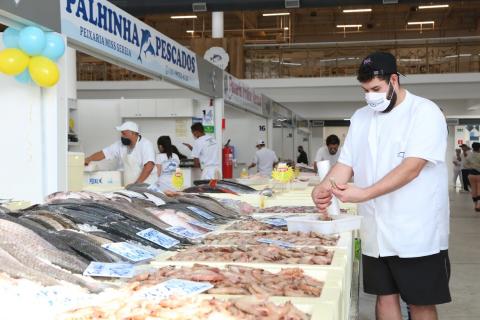 HOmem está junto a box de pescados. #Paratodosverem