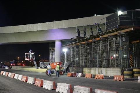 Homens estão no alto de estrutura de ferro aparente removendo o cimbramento. #Paratodosverem