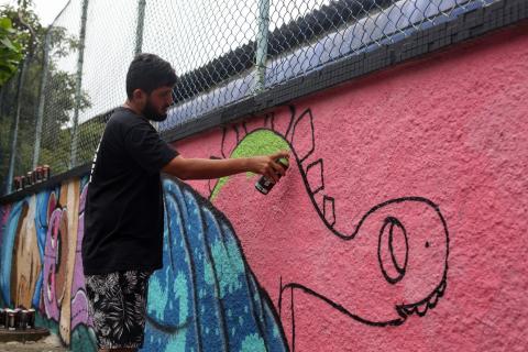 O artista grafitando o muro. #Paratodosverem