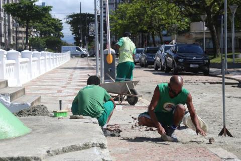 Homens agachados fazem manutenção de mosaico. #Paratodosverem