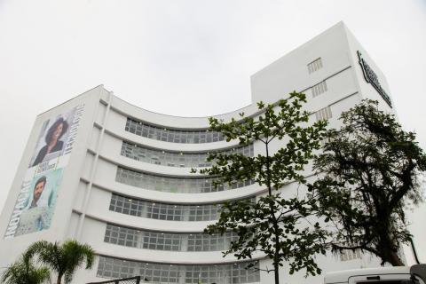 Fachada e vista da parede lateral esquerda com dois grandes banners onde aparecem jovens. #Paratodosverem