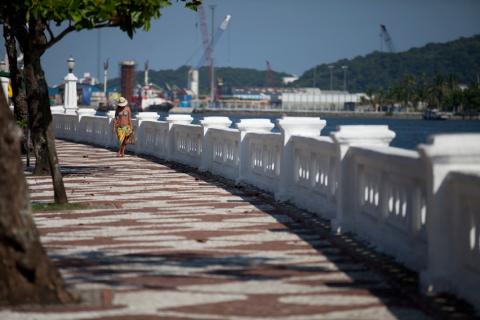 Calçadão da orla com mulher caminhando próximo às muretas.