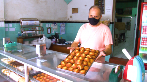 Homem segura bandeja com queijadinhas. #paratodosverem