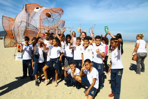 crianças posam ao lado do ecopeixe com garrafas nas mãos #pracegover 