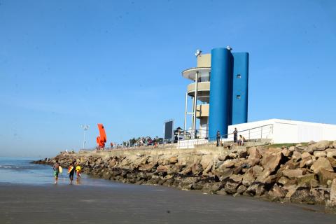 Torre com três pavimentos sobre um pier que avança para o mar. #Pracegover