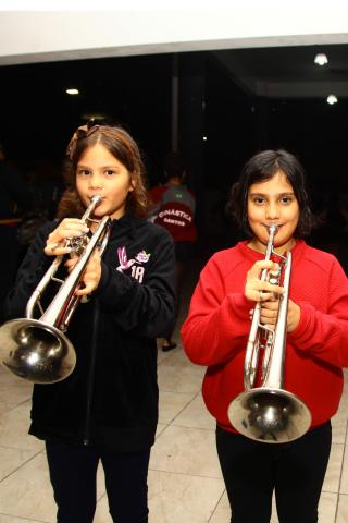 As gêmeas Emmanuelli e Tainá ensaiam com seus instrumentos de sopro. #Pracegover