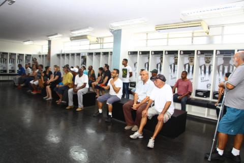 homens estão sentados em vestiário #pracegover