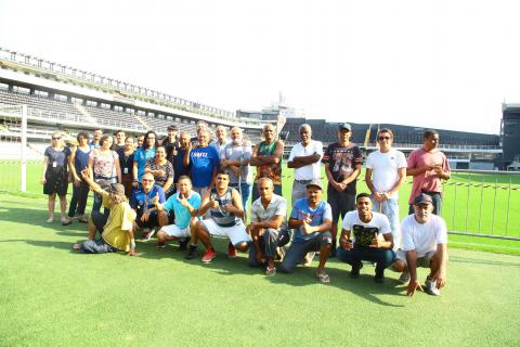 homens fazem pose em foto no gramado #pracegover 