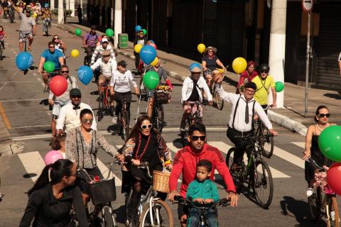 Ciclistas percorrem rua no  Centro. As bicicletas estão decoradas com balões coloridos. #Pracegover