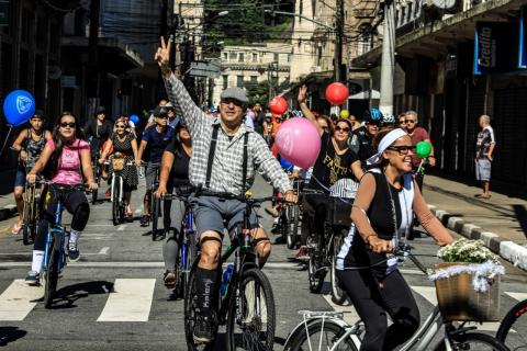 Ciclistas pelas ruas do Centro. Eles estão sorridentes em suas bikes. #Pracegover