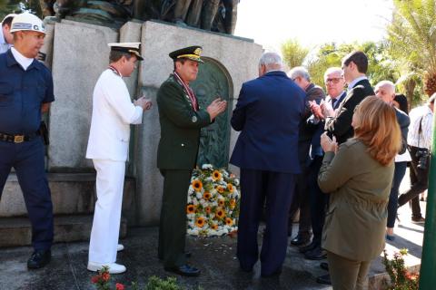 Arranjo de flores é colocado diante de monumento. #Pracegover