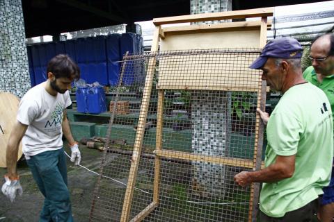 dois operários fazem reparos em grade #pracegover 