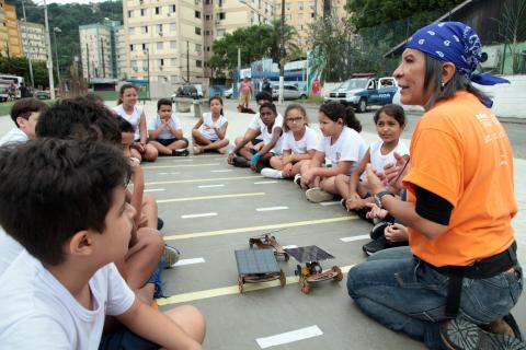 crianças sentadas acompanhando um dos experimentos crianças cercam um dos experimentos #paratodosverem 