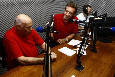 Pepe está à frente de microfone de rádio. Ao lado dele estão dois locutores também à frente de microfones. #Pracegover