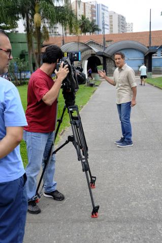 equipe filma rapaz na frente do aquário #pracegover 