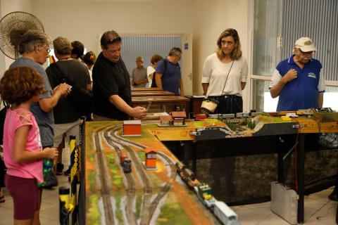 Maquete de ferreomodelismo exposta com o público observando. #Paratodosverem