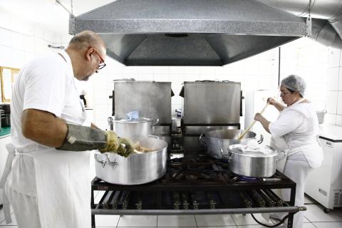 cozinheiros preparam refeições nas panelas #pracegover 