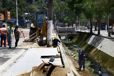 operários e máquina trabalham em borda de canal #pracegover 