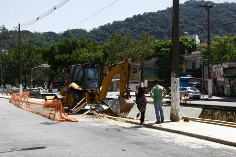 operários e máquina trabalham em borda de canal #pracegover 