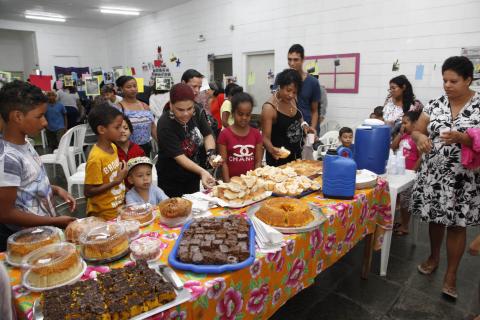 pessoas se servem em mesa de salgados e doces #pracegover 