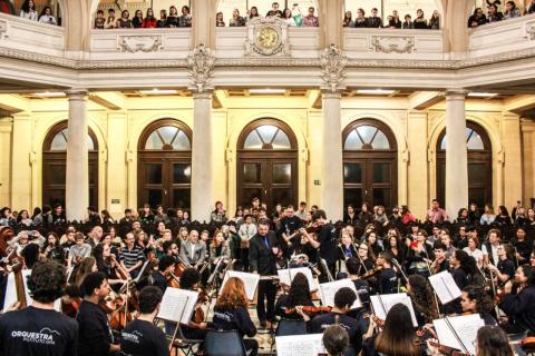 Orquestra sinfônica toca no Museu do Café. No alto se vê as galerias lotadas de público. #Pracegover