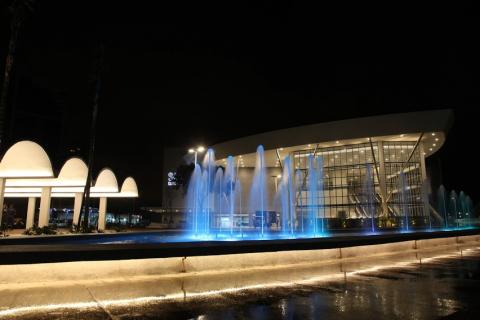 Centro de Convenções à noite com fonte luminosa à frente. #pracegover